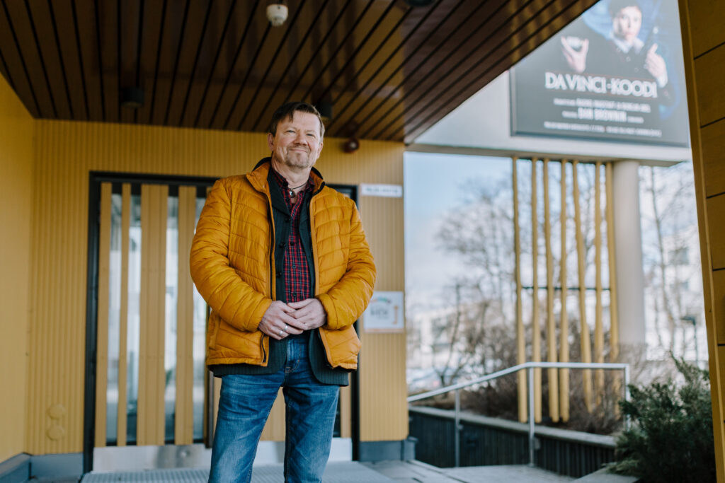 Teatterinjohtaja Timo Rissanen seisoo Imatran kaupunginteatterin ulko-ovella hymyillen.