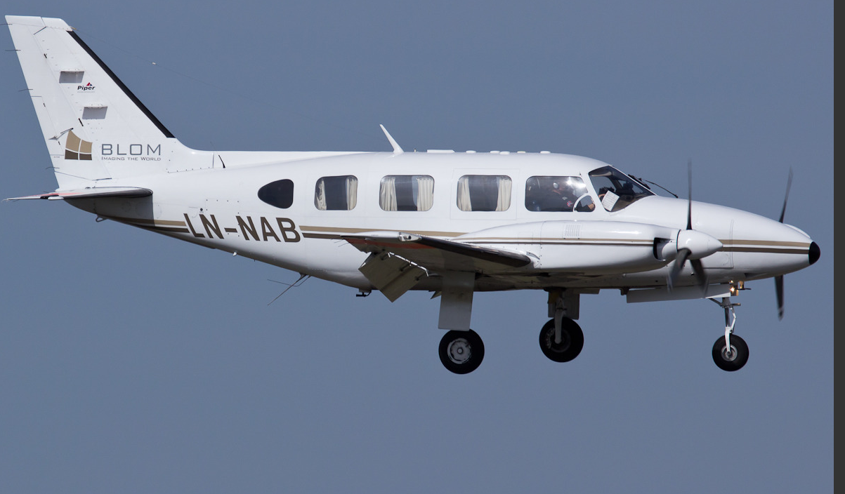 Sinisellä taivalla lentää pieni, kaksimoottorinen lentokone.